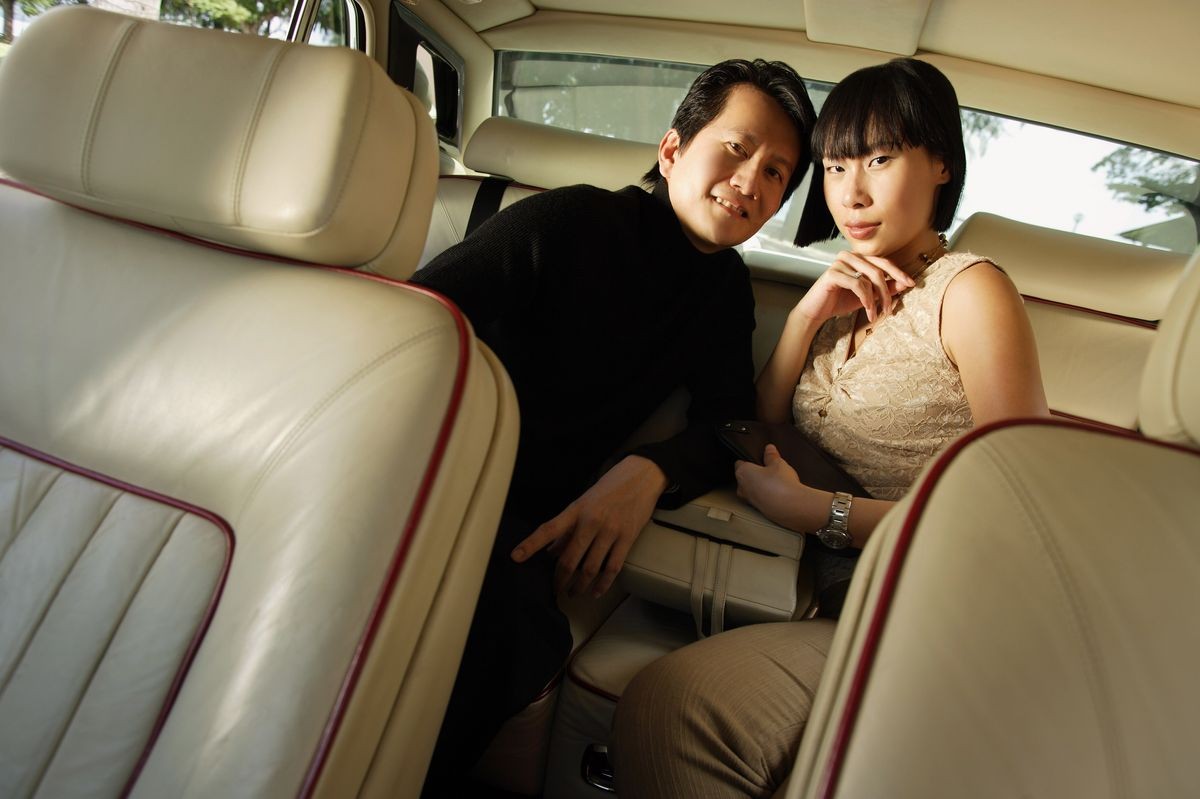 Couple sitting in backseat of car, looking at camera